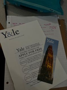 a pile of papers sitting on top of a desk next to a blue bag and pen