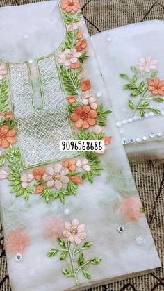 two pieces of embroidered fabric with flowers and leaves on them, sitting on a table