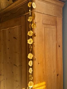 a wooden cabinet with yellow flowers hanging from it's sides