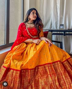 a woman in a yellow and red lehenga sitting on a window sill