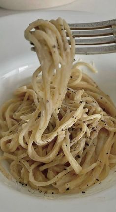 a fork with some noodles in it on a white plate