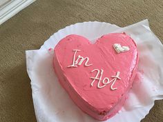 a pink heart shaped cake with the words i'm hot on it sitting on top of a paper plate