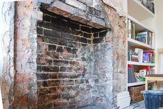 an old brick fireplace in the corner of a room with bookshelves on either side