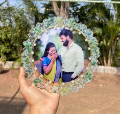 a hand holding up a glass photo frame with an image of a man and woman