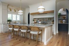 a large kitchen with an island and marble counter tops in the center is surrounded by white cabinets