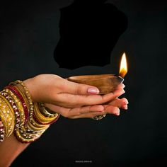 a woman's hand holding a small wooden bowl with a lit candle in it