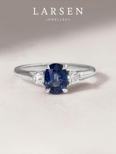 a blue sapphire and diamond ring with three diamonds on the side, in white gold