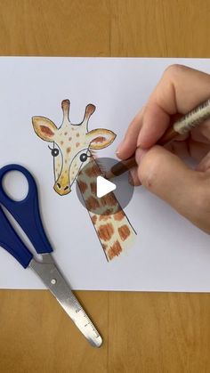 a person cutting out a giraffe's face with scissors on a piece of paper