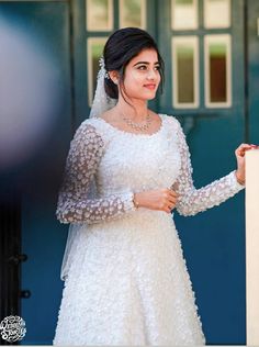 a woman in a white wedding dress standing next to a blue door wearing a tiara