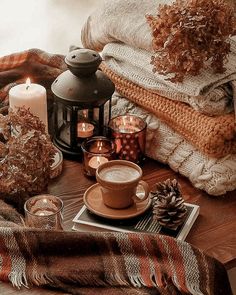 a table topped with candles and blankets next to a cup of hot chocolate on top of a plate