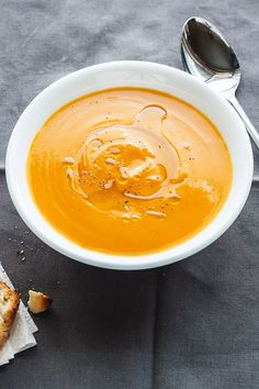 there is a bowl of soup with bread on the table next to it and a spoon