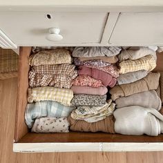 an open drawer filled with clothes on top of a wooden floor