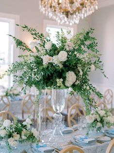 a vase filled with white flowers sitting on top of a table next to plates and glasses