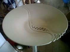 a large white bowl sitting on top of a wooden floor next to a table and chairs