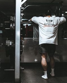 a man standing in front of a gym machine with his back turned to the camera