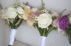 three white vases filled with different types of flowers