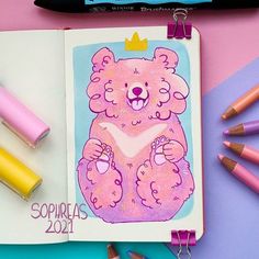 a drawing of a pink bear with a crown on its head, surrounded by crayons