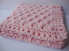 a pink crocheted blanket sitting on top of a table