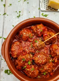 a brown bowl filled with meatballs covered in sauce