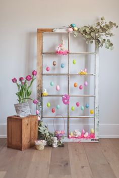 an old ladder with easter decorations and flowers on it in front of a white wall