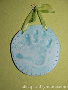 a handprint ornament hanging on the wall with a green ribbon around it