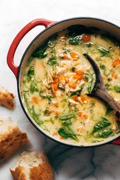 a red pot filled with soup next to bread