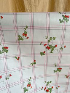 the fabric is white with red and green flowers on it, along with plaid pattern