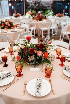 the table is set with plates, silverware and floral centerpieces on it