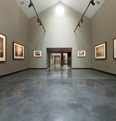 an empty room with paintings on the walls and flooring in it, along with pictures hanging on the wall