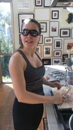 a woman wearing sunglasses is preparing food in the kitchen