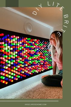 a woman sitting on the floor in front of a wall with colorful lights painted on it