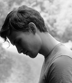 black and white photograph of a young man looking down at his cell phone in the park