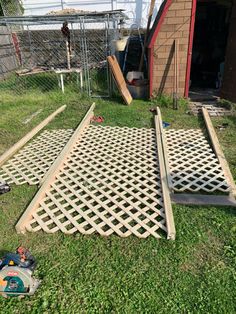 several pieces of wood laying on the grass in front of a building with a fence