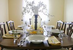 a dining room table is set with dishes and place settings