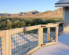 a wooden fence on the side of a building with mountains in the background and snow on the ground