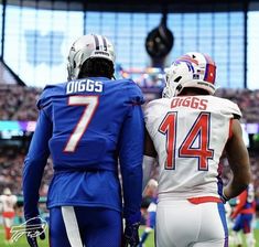 two football players standing next to each other in front of a stadium full of people