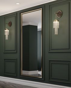 an empty room with green walls and gold framed mirrors