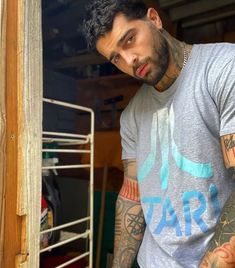 a man with tattoos standing next to a door