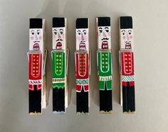 four wooden toy soldiers are lined up against a white background with black and red trim