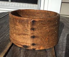 a wooden bowl sitting on top of a wooden table next to a white window sill