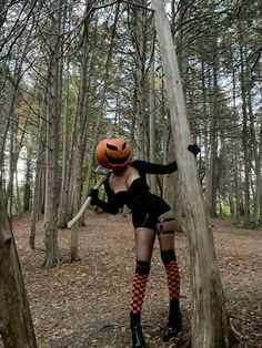 a woman dressed up as a witch in the woods with a pumpkin on her head