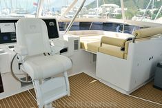 the inside of a boat with lots of white furniture and sailboats in the background