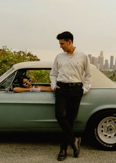 a man standing next to a green car