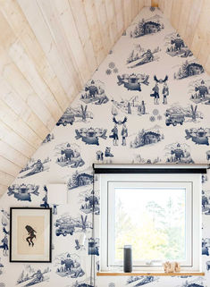 a room with a window and wallpaper that has pictures on the side of it