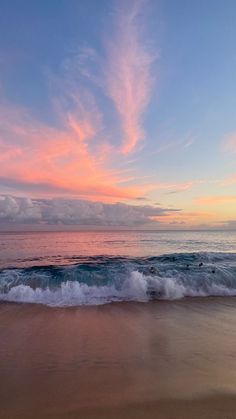 an ocean beach with waves coming in to shore and the sun setting on the horizon