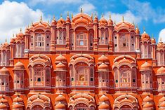 an ornate building with many windows and balconies on the top floor, against a blue sky with wispy clouds