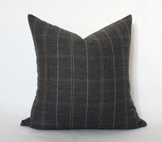 a gray and brown plaid pillow sitting on top of a white wall