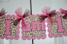 a pink and brown leopard print banner with the word i am 1 on it