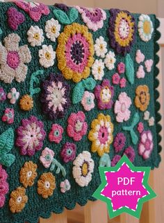 a crocheted blanket with flowers on it hanging from a wooden rail in front of a wall