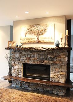 a living room with a stone fireplace and painting on the wall above it's mantle